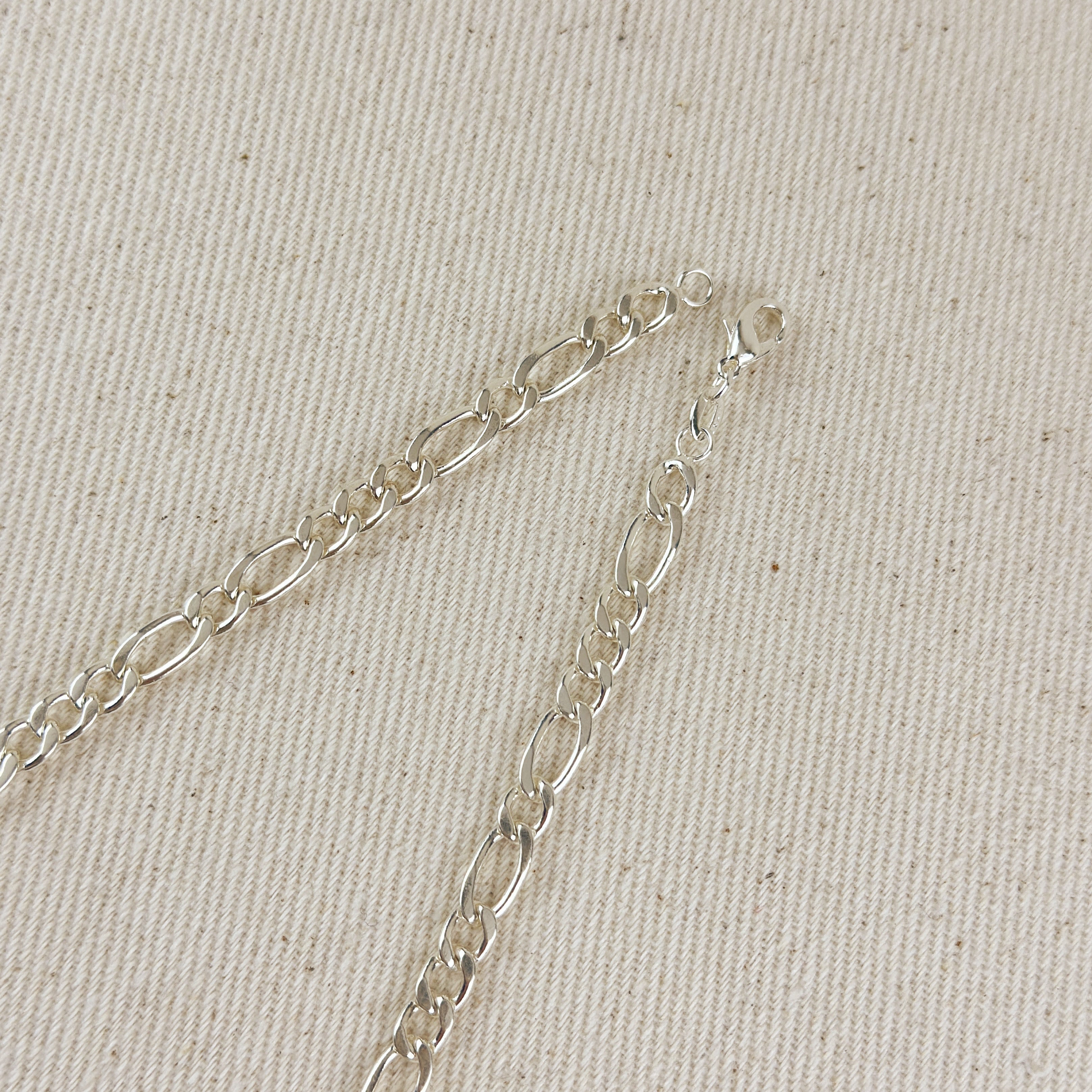 Silver chain bracelet on a beige fabric background