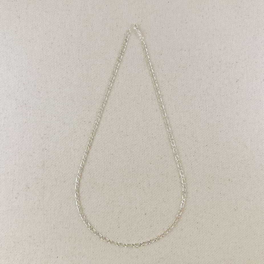 Silver chain necklace on a beige fabric background