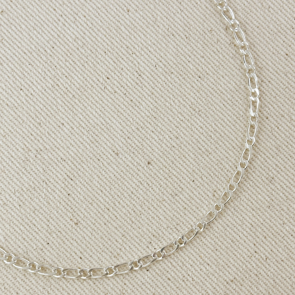 Silver chain necklace on a beige fabric background