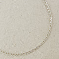 Silver chain necklace on a beige fabric background