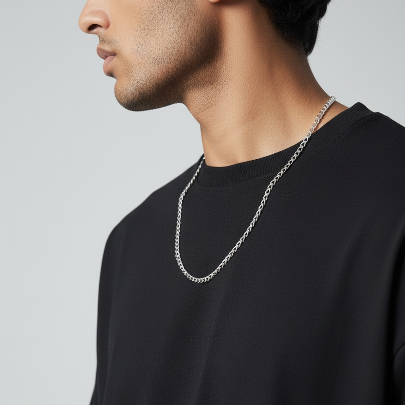 Man wearing a black shirt and silver chain necklace against a gray background