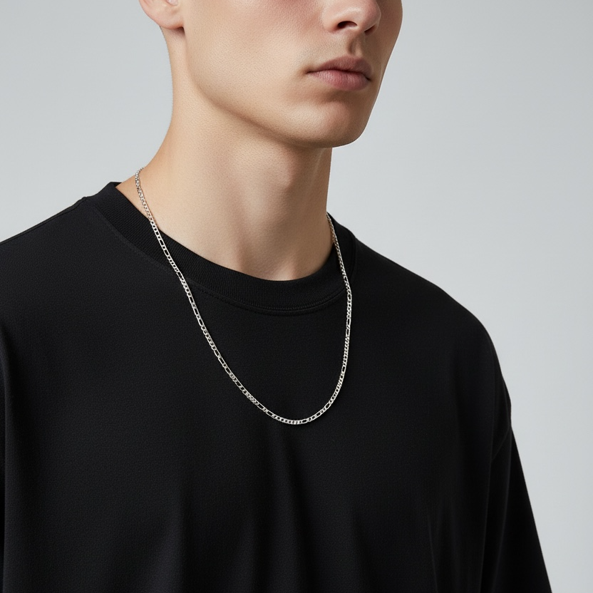 Person wearing a black t-shirt and silver chain necklace on a plain background