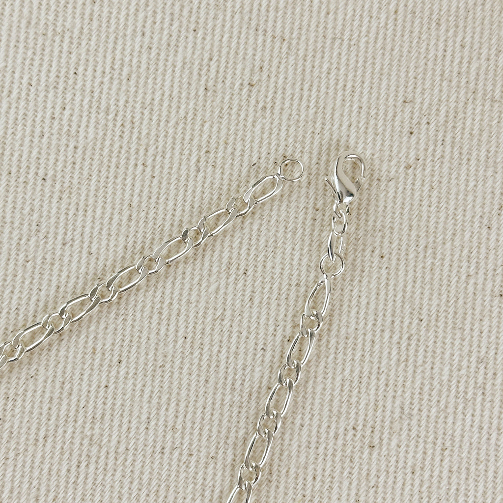 Silver chain necklace on a beige fabric background