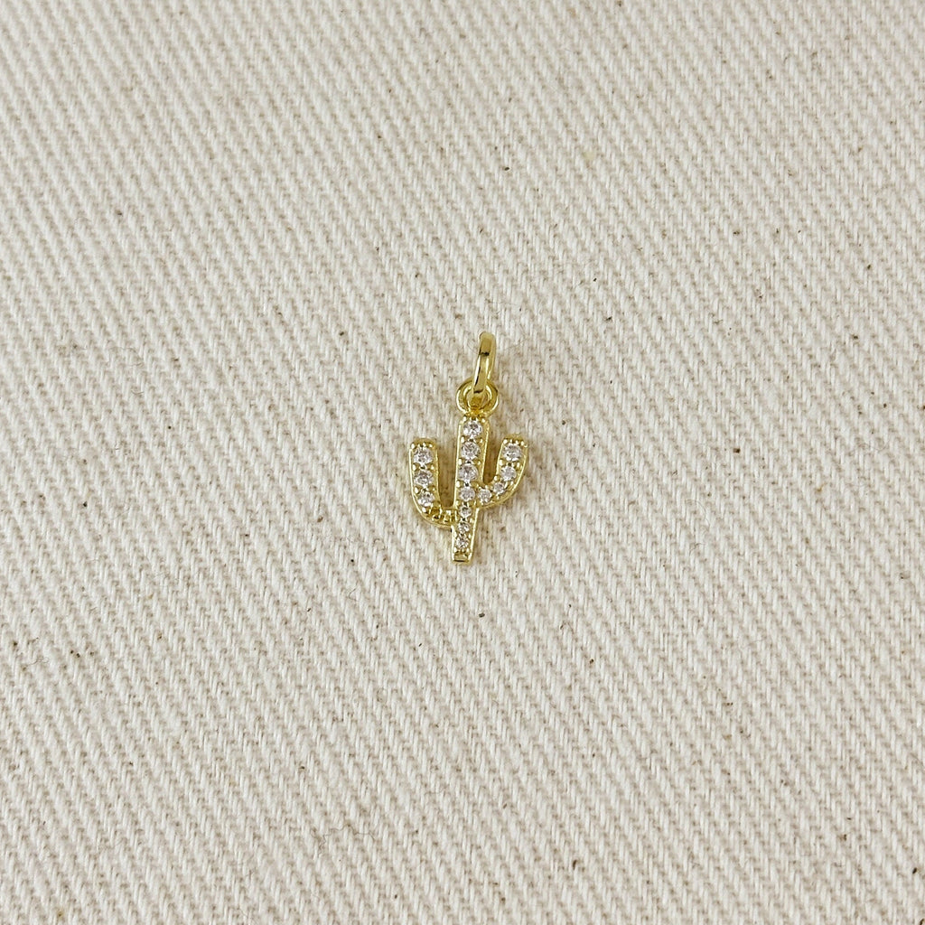 Gold cactus-shaped pendant on a beige fabric background