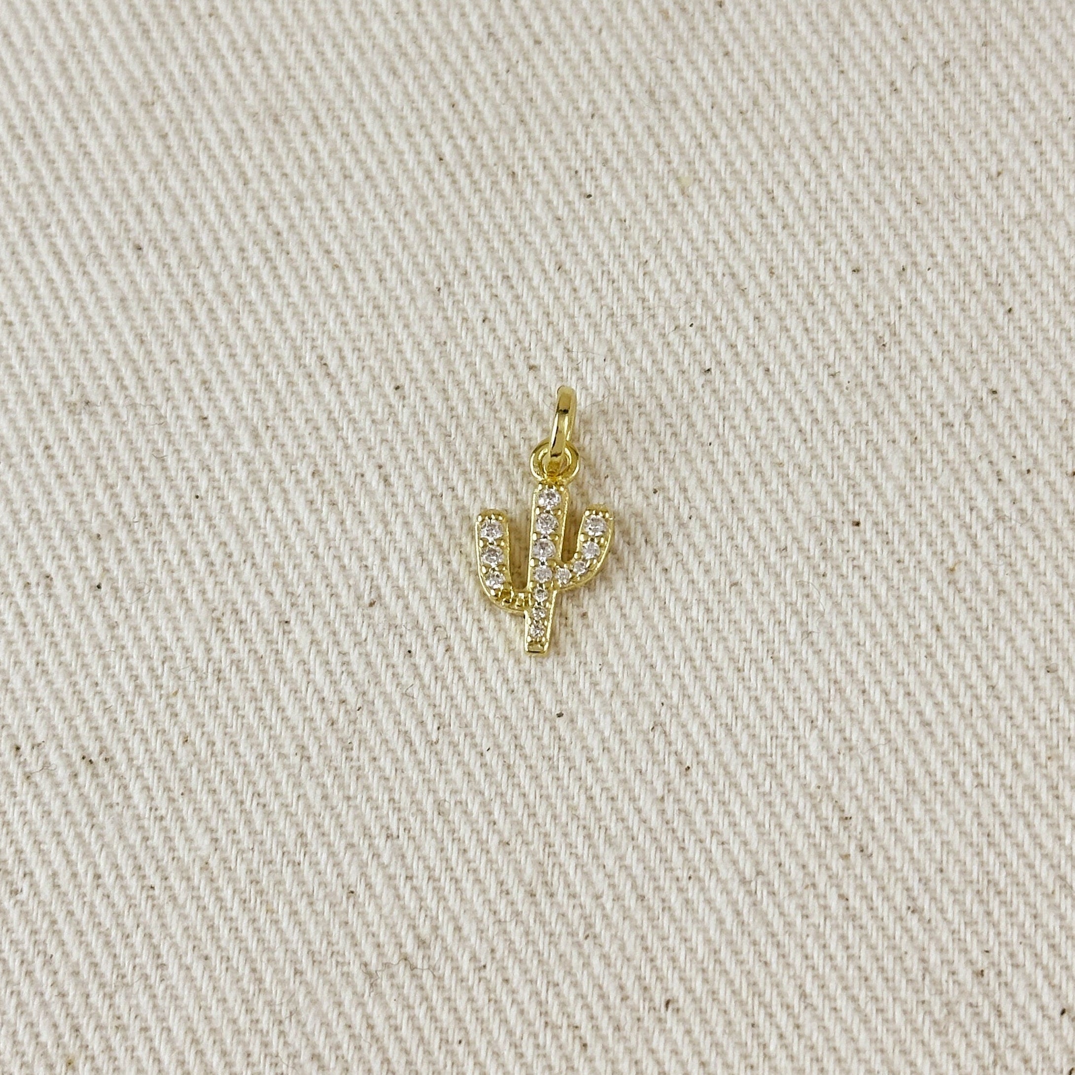 Gold cactus-shaped pendant on a beige fabric background