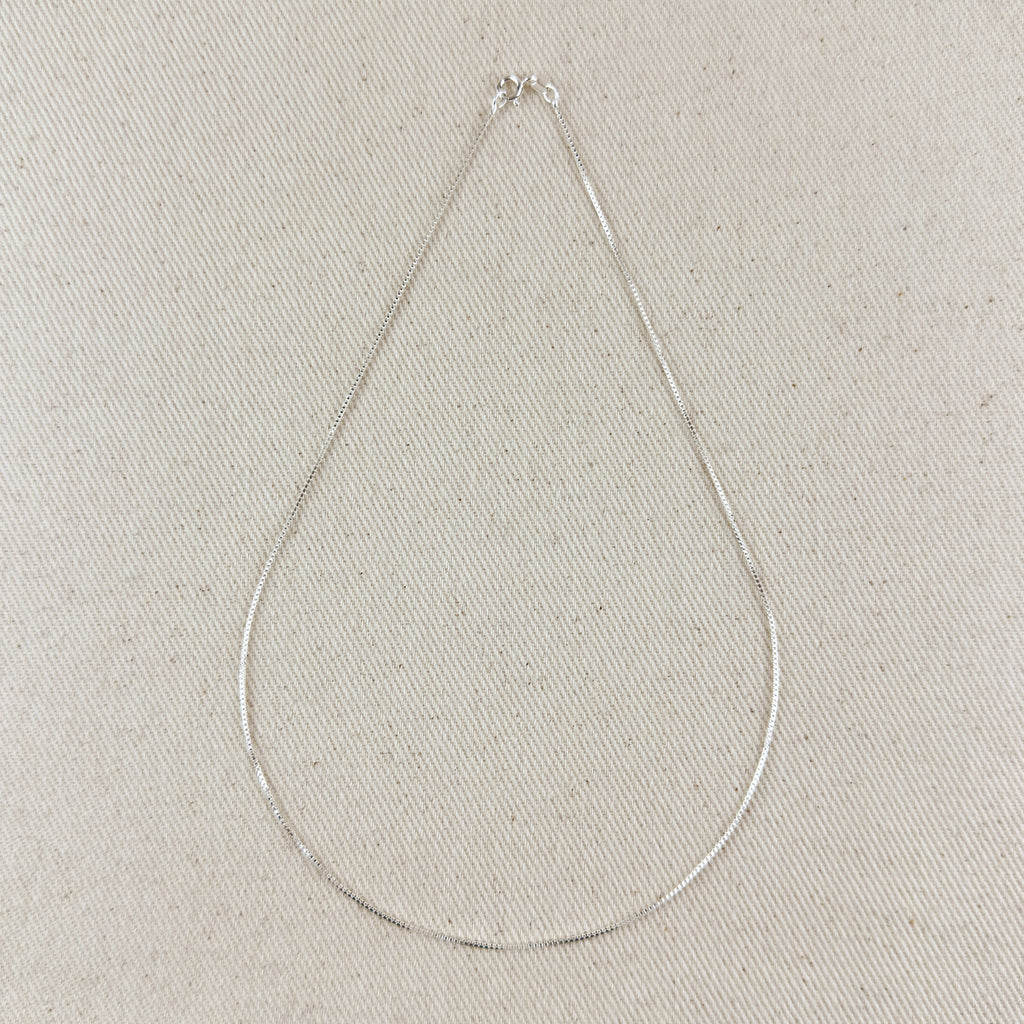 Silver necklace on a light gray textured background