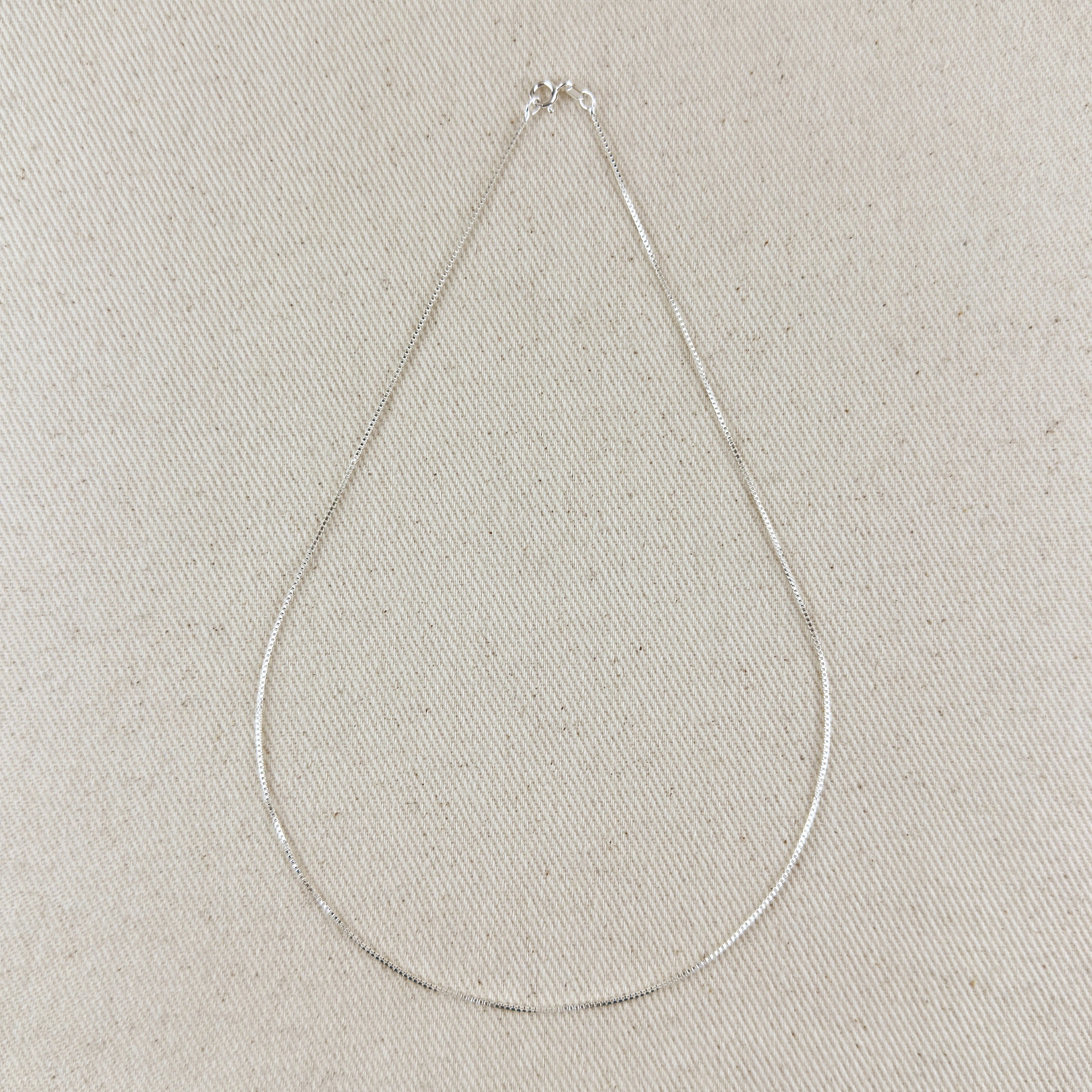 Silver necklace on a light gray textured background