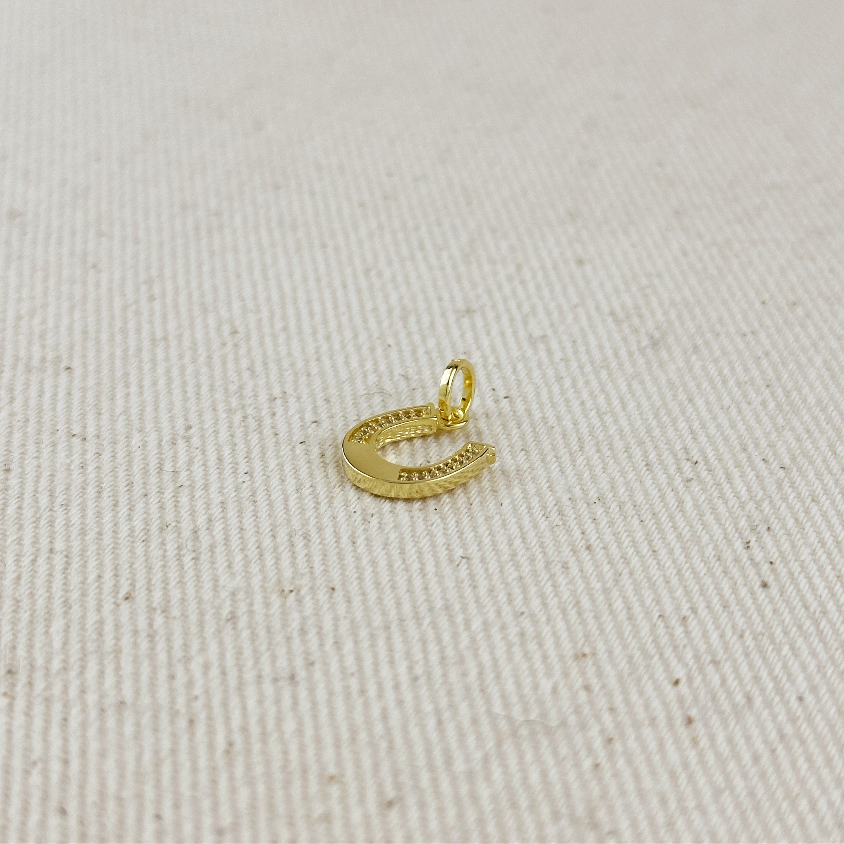 Gold pendant on a light beige fabric background