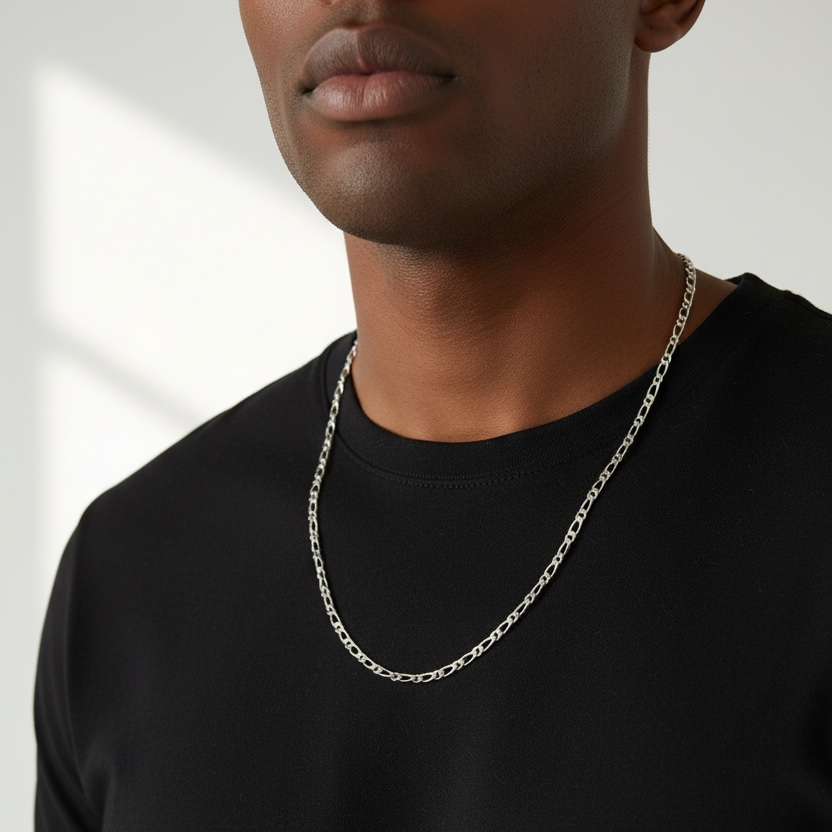Man wearing a black t-shirt and silver chain necklace against a neutral background