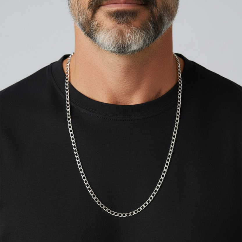 Man wearing a black shirt with a silver chain necklace against a gray background