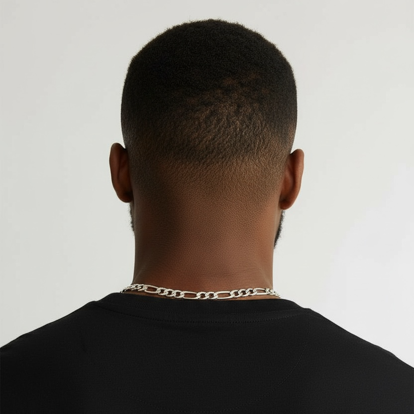Man wearing a black shirt with a gold chain necklace on a plain background