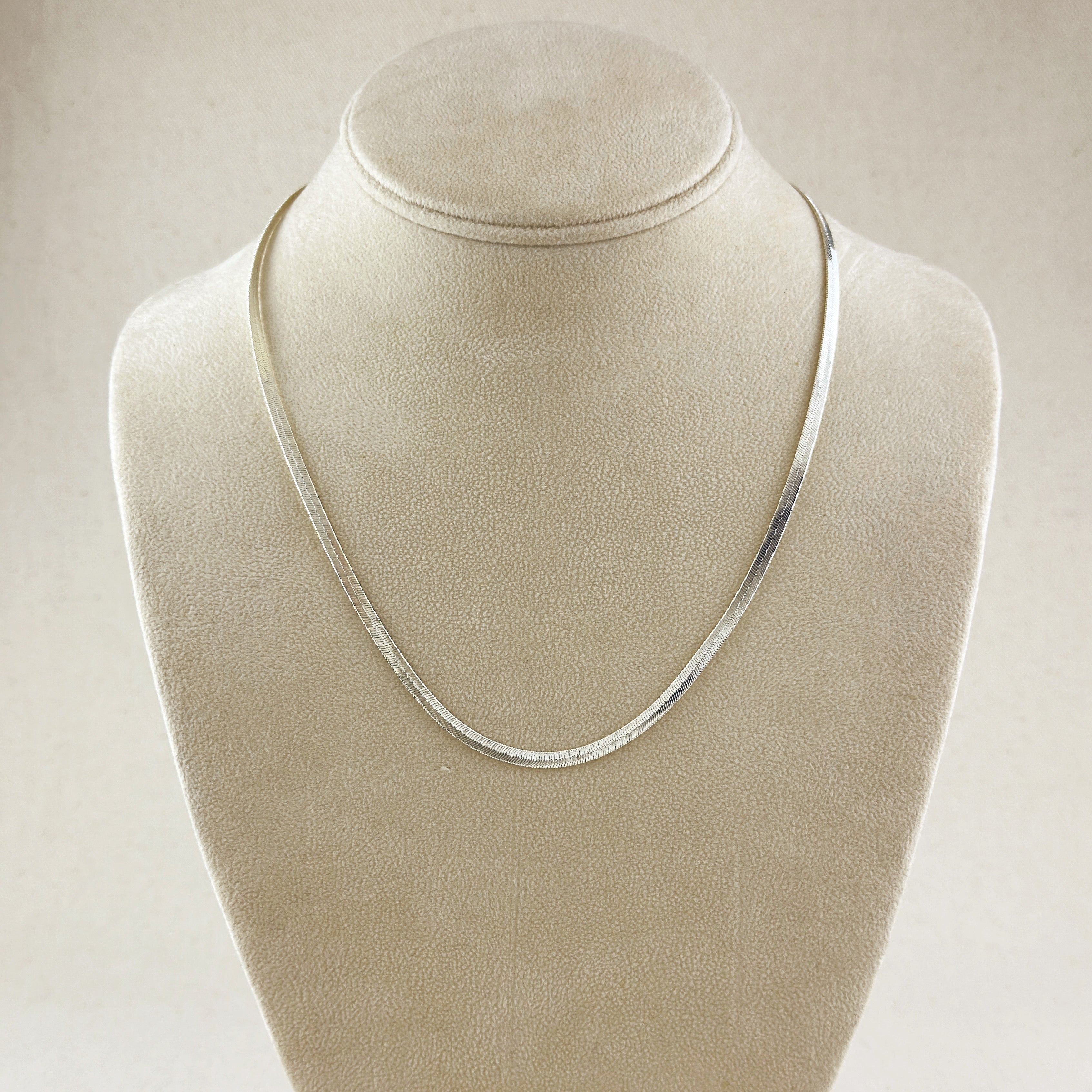 Silver necklace on a beige velvet mannequin bust